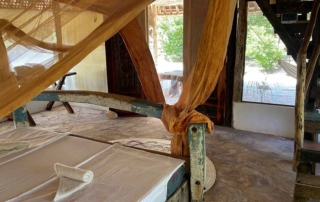 view on king size bed made of old boat with orange mosquito net and stairs and outside terrace