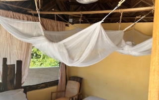 2 single beds with musquitonets in affordable comfort budget rooms with beds made of recycled wood of boats.